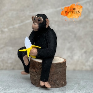 May include: A black felt chimpanzee toy sitting on a wooden stump, holding a yellow felt banana. The toy has a white felt banana peel.