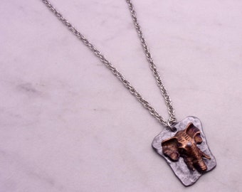 May include: A silver chain necklace with a silver and copper pendant featuring an elephant head design.