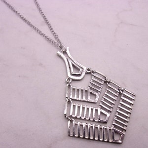 May include: A silver necklace with a geometric pendant. The pendant is made of thin metal bars that are arranged in a diamond shape. The necklace is a great addition to any jewelry collection.