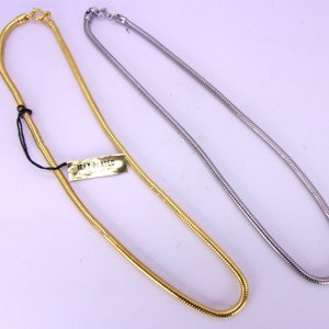 May include: Two snake chain necklaces, one gold and one silver. The gold necklace has a tag that says "18KY PLATED".