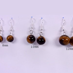 May include: Three pairs of tiger's eye earrings with silver hooks. The earrings are available in three sizes: 8mm, 10mm, and 12mm.