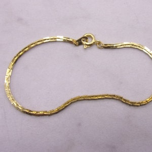 May include: A gold chain bracelet with a simple, boxy link design.