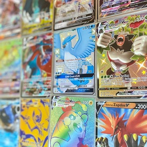 May include: A collection of Pokemon trading cards featuring various characters and abilities. The cards are holographic and have colorful illustrations. Some of the cards include Rillaboom VMAX, Morpeko VMAX, and Galarian Zapdos V.