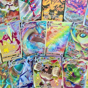 May include: A collection of Pokemon trading cards featuring various characters, including Toxtricity V, Snorlax V, and Calyrex V. The cards are holographic and have a rainbow foil finish.