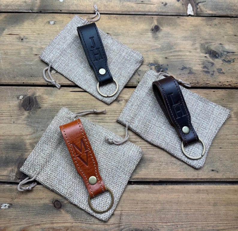 May include: Three leather keychains with personalized initials. Each keychain is brown, black, or tan and comes with a small burlap pouch.