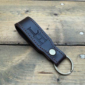 May include: A brown leather keychain with a metal ring and the initials "LH" embossed on the leather.