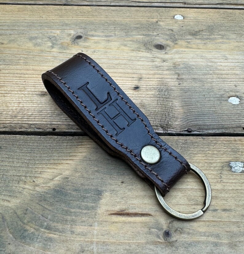 May include: A brown leather keychain with a metal ring and the initials "LH" embossed on the leather.