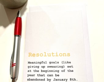 May include: A white card with the text "Resolutions" in yellow. The text below reads "Meaningful goals (like giving up swearing) set at the beginning of the year that can be abandoned by January 8th."