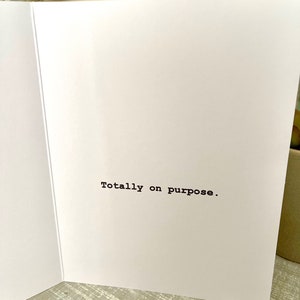 May include: A white card with the text "Totally on purpose." printed in black.