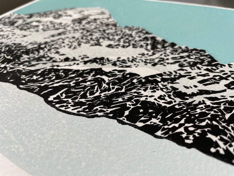 May include: A black and white print of a mountain range with a light blue background.