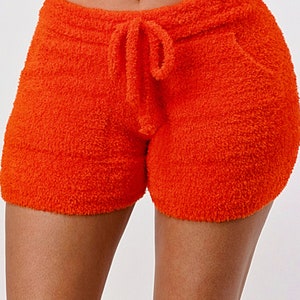 May include: Orange fuzzy shorts with a drawstring waist.