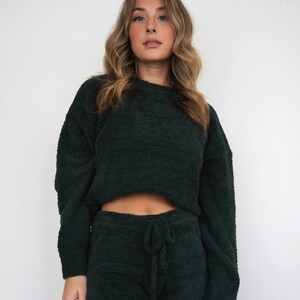 May include: A dark green fuzzy sweater and shorts set. The sweater is cropped and the shorts have a drawstring waist.