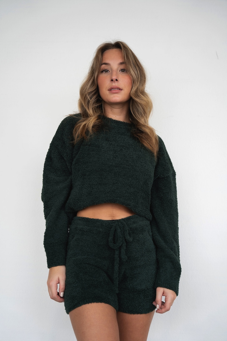 May include: A dark green fuzzy sweater and shorts set. The sweater is cropped and the shorts have a drawstring waist.