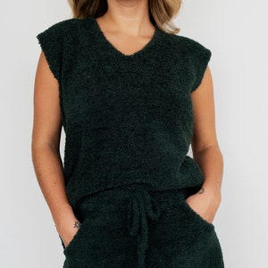 May include: A dark green fuzzy sleeveless top and matching shorts set. The top has a v-neck and the shorts have a drawstring waist.