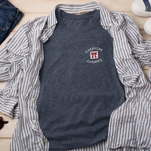 May include: A dark blue t-shirt with a white and red embroidered logo that says "Rakkasan Raiders" and features a red Japanese torii gate.
