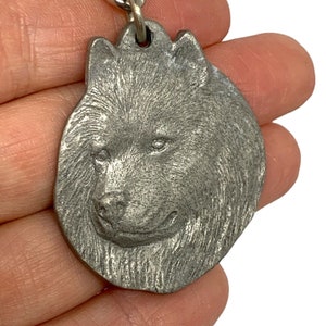 May include: A silver metal keychain charm featuring a detailed, realistic depiction of a husky dog's head.