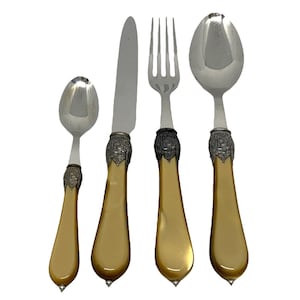 May include: A set of four gold-handled silverware pieces, including a knife, fork, and two spoons. The handles are a rich gold color and have intricate designs.