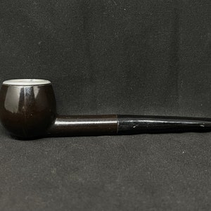 May include: A black wooden pipe with a round bowl and a long, slender stem.