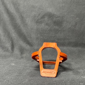 May include: An orange plastic Atomic ski boot holder. The holder has a rectangular base with the word "Atomic" embossed on it. The holder has a curved top and two side supports.