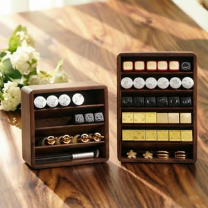 Könnte beinhalten: Zwei dunkle Holz-Organizer gefüllt mit verschiedenen kleinen Gegenständen. Einer enthält Lippenstifte, einen Make-up-Pinsel und andere Schönheitsprodukte. Der andere enthält Ohrringe, Ringe und anderen Schmuck. Die Organizer stehen auf einer Holzoberfläche.