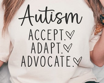 May include: A white t-shirt with the text "Autism Accept. Adapt. Advocate." in black lettering with a heart symbol after each word.