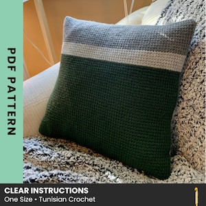May include: A square, crocheted pillow with a dark green base, a gray middle section, and a thin white stripe. The top section is gray. The text "PDF PATTERN" is on the left side. The text "CLEAR INSTRUCTIONS One Size • Tunisian Crochet" is at the bottom.