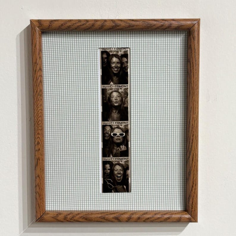 May include: A vertical photo strip featuring four black and white portraits of a person, each labeled Hotel Clermont, displayed in a rectangular wooden frame with a light green and white gingham fabric matting surrounding the central image.