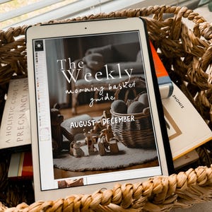 May include: A digital tablet displaying a printable guide for a weekly morning basket. The guide is titled "The Weekly Morning Basket Guide" and includes the months August through December. The tablet is sitting in a wicker basket with other books.