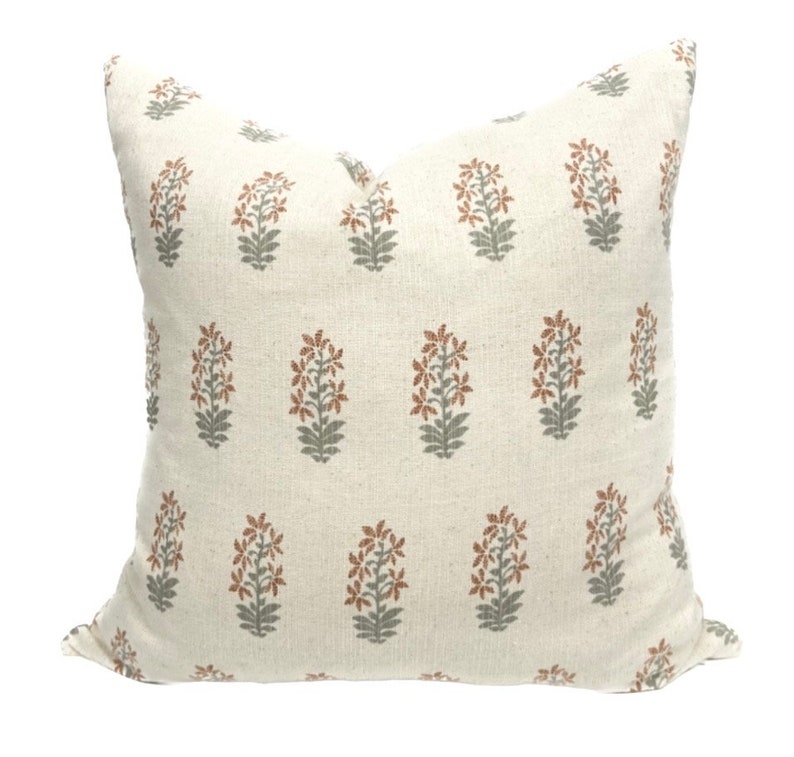 May include: A white pillow with a floral pattern in shades of brown and green. The pillow is made of a soft, textured fabric.