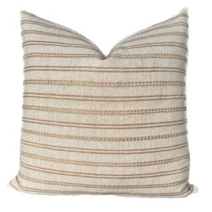 May include: A beige and brown striped throw pillow with a subtle woven texture. The pillow is made of a soft, comfortable fabric and has a simple, elegant design.