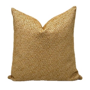 May include: A square throw pillow with a yellow and white geometric pattern. The pillow is made of a textured fabric.