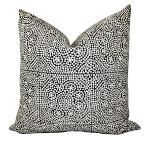 May include: Black and white throw pillow with a geometric pattern of small white circles and stars.
