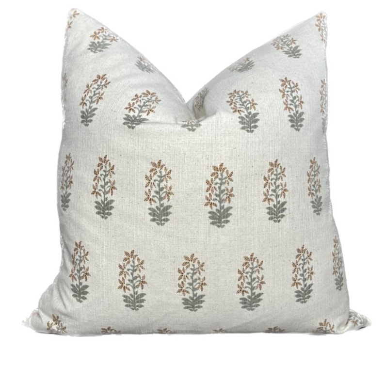 May include: A white pillow cover with a repeating pattern of gray and brown floral designs.