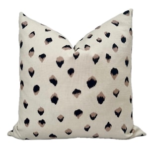 Könnte beinhalten: Ein weißes Kissen mit einem schwarzen und braunen Tierdruckmuster. Das Kissen ist aus einem weichen, strukturierten Stoff.