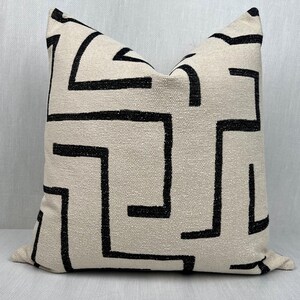 May include: A white pillow with a black geometric pattern. The pattern is made up of lines and squares.