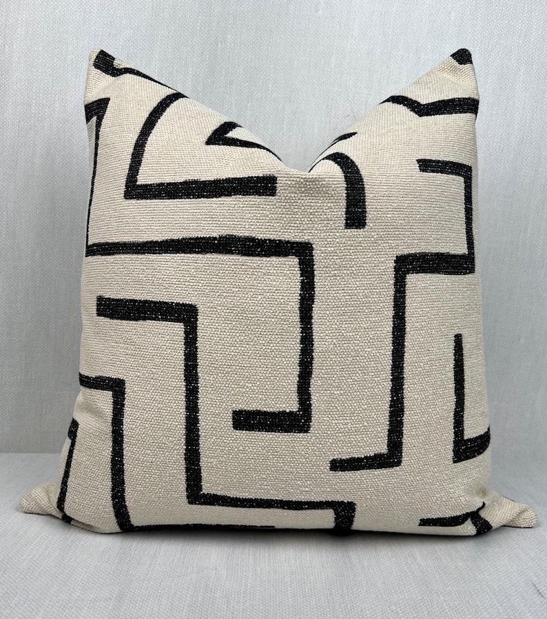 May include: A white pillow with a black geometric pattern. The pattern is made up of lines and squares.
