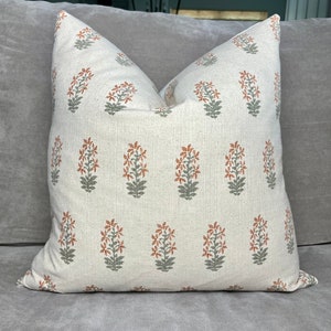 May include: A white throw pillow with a repeating pattern of orange and green floral designs.