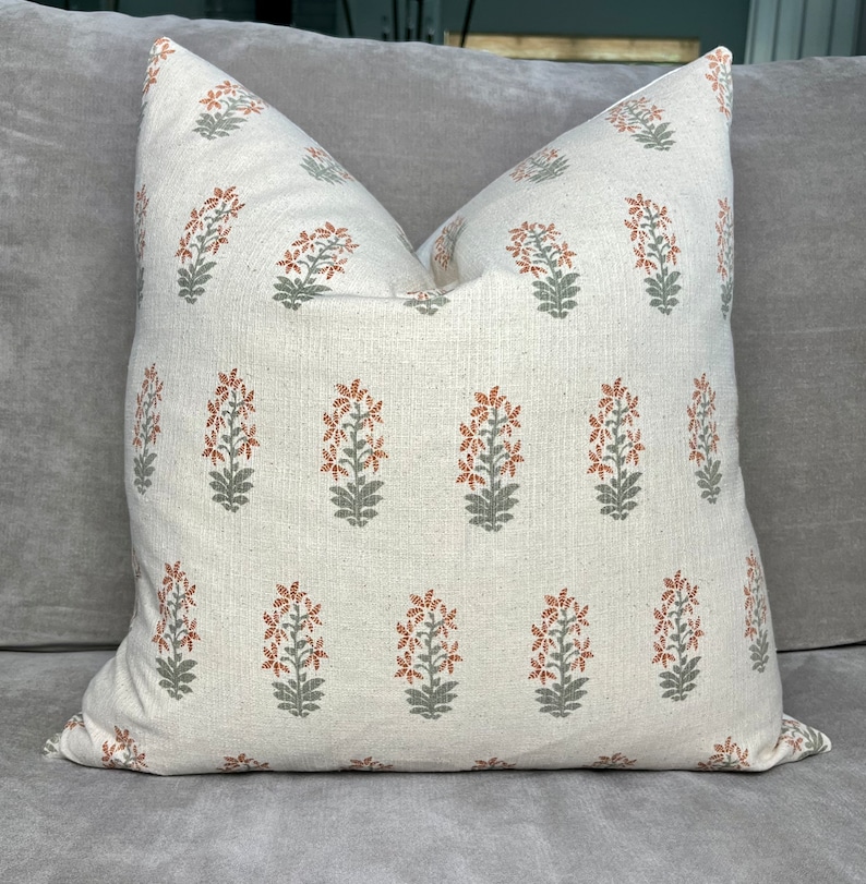 May include: A white throw pillow with a repeating pattern of orange and green floral designs.