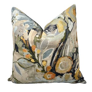 May include: A decorative throw pillow with a floral pattern in shades of beige, blue, green, black, and yellow. The pillow features abstract brushstrokes and a painterly style.