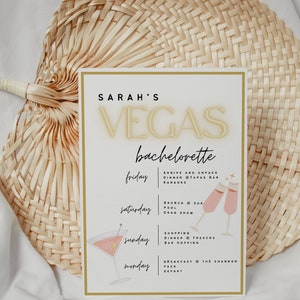 Puede incluir: Una tarjeta blanca con borde dorado y texto negro que describe un itinerario de despedida de soltera para un viaje a Las Vegas. La tarjeta enumera las actividades para cada d&iacute;a del viaje, incluyendo cena, karaoke, brunch, piscina, espect&aacute;culo de drag, compras y desayuno.