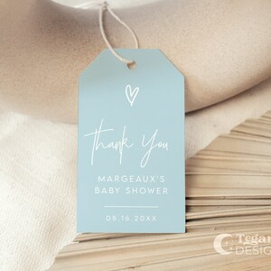 May include: A light blue thank you tag with a white heart and the text "Thank You, Margeaux's Baby Shower, 05.16.20XX".
