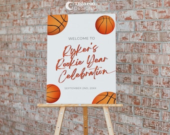 Peut inclure: Bienvenue à la célébration de l'année recrue de Ryker, une pancarte blanche avec des ballons de basket orange et le texte en rouge.