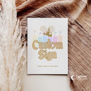 May include: A white card with a gold glitter castle silhouette and the text "Custom Sign" in gold glitter. The text "Insert Custom Text Here" is below the sign.