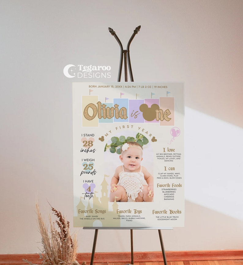 Op de afbeelding: Een pastelkleurig eerste verjaardagsbord met een foto van een babymeisje. Het bord bevat de naam van de baby, Olivia, en details over haar eerste jaar, inclusief haar lengte, gewicht en favoriete dingen. Het bord is versierd met een gouden glitter-&eacute;&eacute;n, een Mickey Mouse-hoofd en een bloemenkrans.