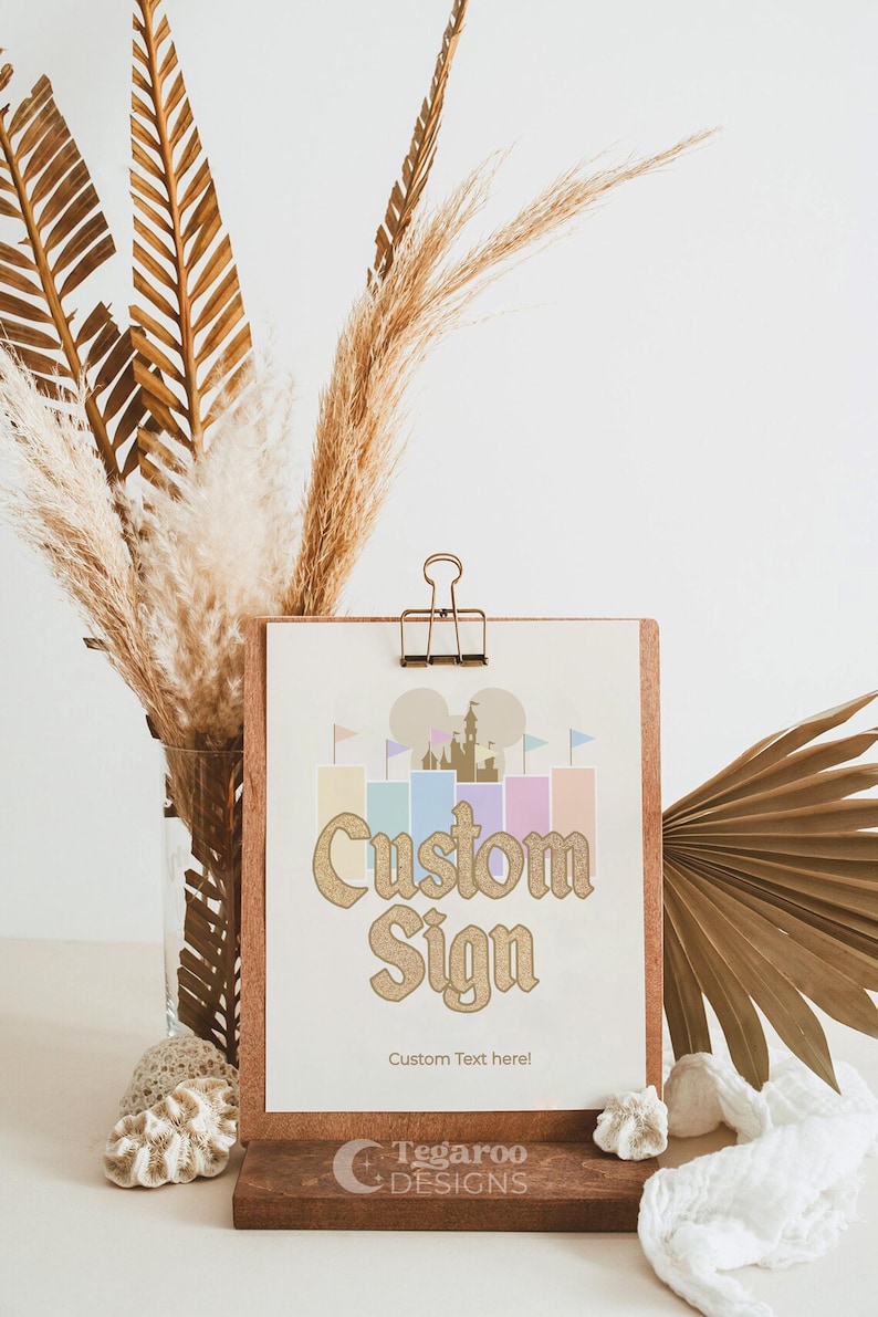 May include: A wooden sign with a gold glitter castle graphic and the text "Custom Sign" with the words "Custom Text here!" below. The sign is on a wooden stand with the text "Tegaroo Designs" on the front.