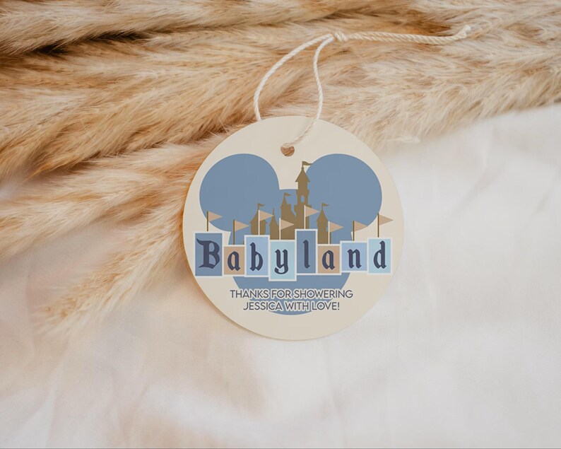 May include: A round, cream-colored tag with a blue and tan castle design and the word "Babyland" in blue letters. The tag has a string attached and the text "THANKS FOR SHOWERING JESSICA WITH LOVE!"