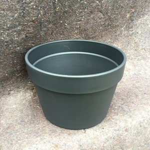 May include: A dark gray plastic plant pot with a wide rim.