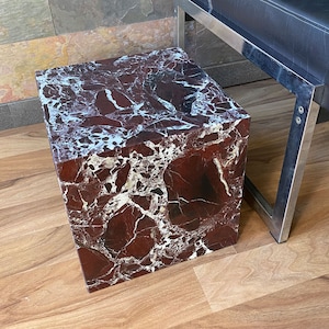 Può includere: Un tavolino da salotto cubico in marmo rosso e bianco con una superficie liscia e lucida.