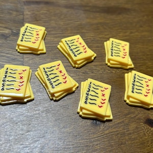 May include: Seven yellow paper score cards with black numbers and red check marks. The cards are stacked on top of each other.
