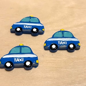 May include: Three blue toy taxi cars with yellow tops and white stripes. Each car has the word "TAXI" printed on the side.